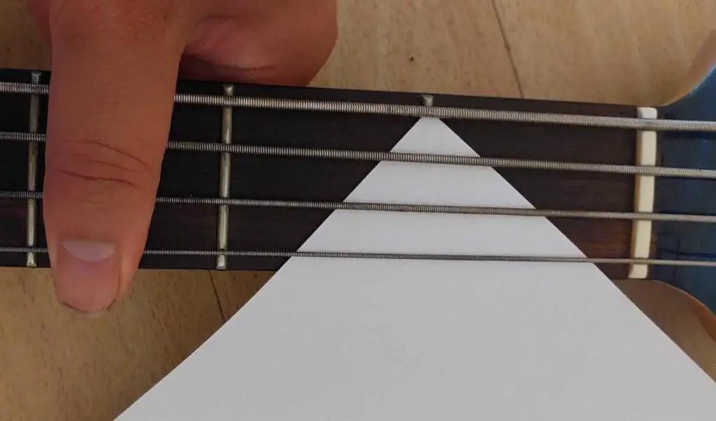 bass nut height being checked using sheet of paper