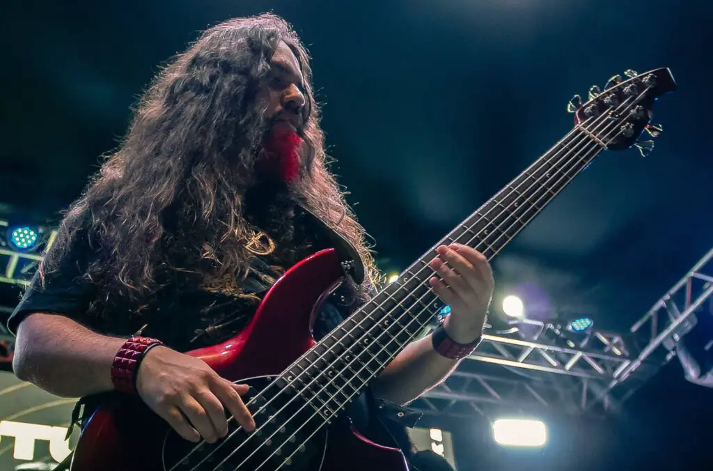 intermediate bass player playing 6-string bass on stage