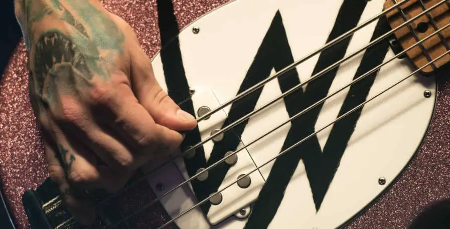 bass player playing with a pick on a pink 4-string