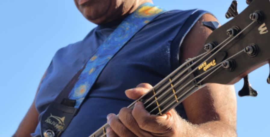 bassist playing a 5-string with a wide bass strap