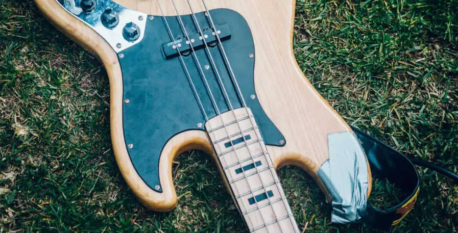 damaged 4-string bass laying on grass