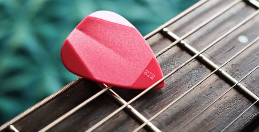 guitar strings with pick on top of them