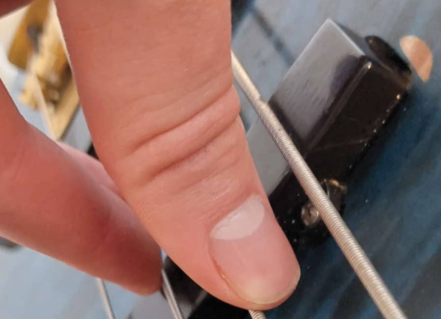 thumb resting on strings on 4-string bass