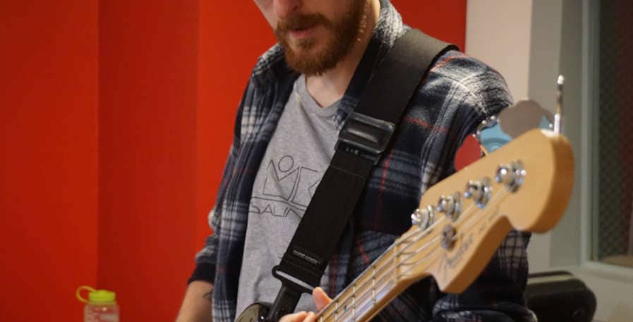 bass player looking down at 4-string fender bass guitar