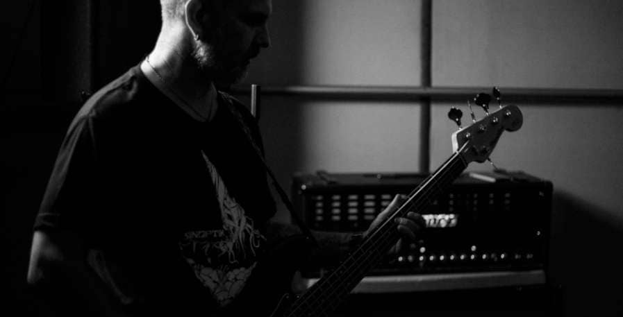 metal bassist playing 4-string bass in front of bass amp