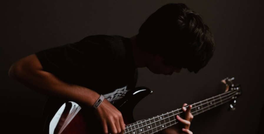 young bassist playing 4-string bass with rattling strings