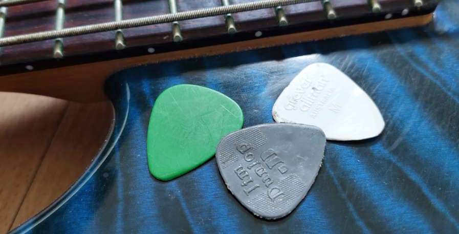 bass picks in different thicknesses on top of bass guitar