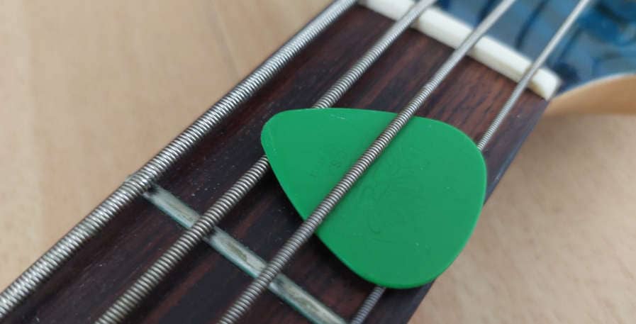 medium gauge bass pick fastened to 4-string bass guitar