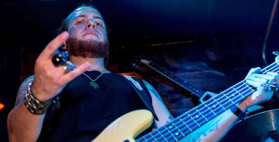 metal bassist standing on stage with 5-string bass