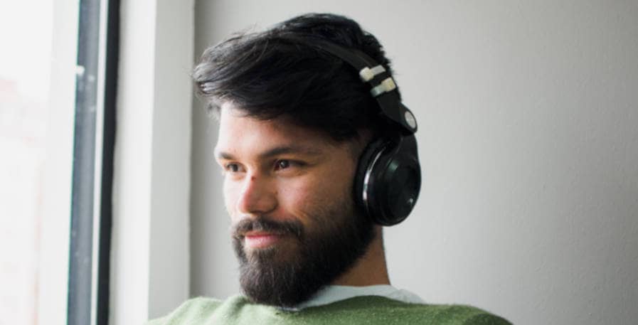 happy man in sweater listening to song on headphones