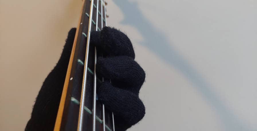 fretting hand with glove on playing a bass note