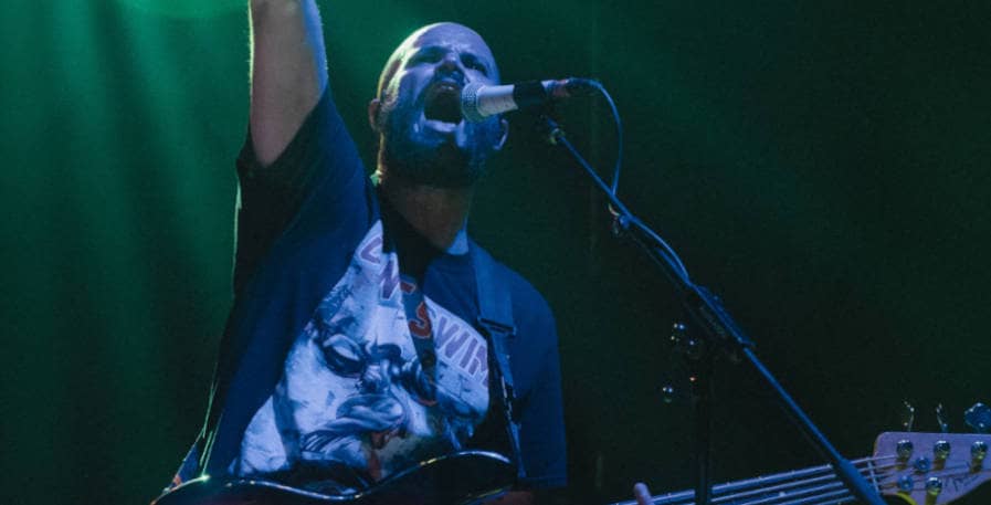 metal bass player yelling into microphone while holding 5-string bass