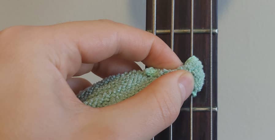 bass strings being cleaned by wrapping cloth around them